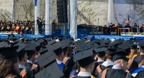 Students in cap and gowns sitting at graduation