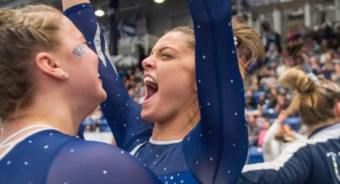 UNH gymnast throwing her hands up and cheering