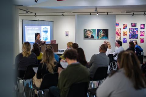 People gathered at an art gallery listening to a presentation