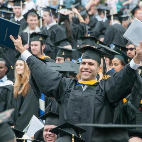 Accelerated masters student smiling and standing at graduation