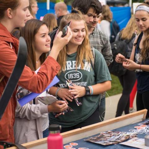 Group of students smiling and standing in front of table at UNH fair