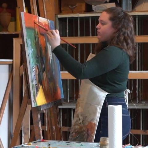 Student painting at easle