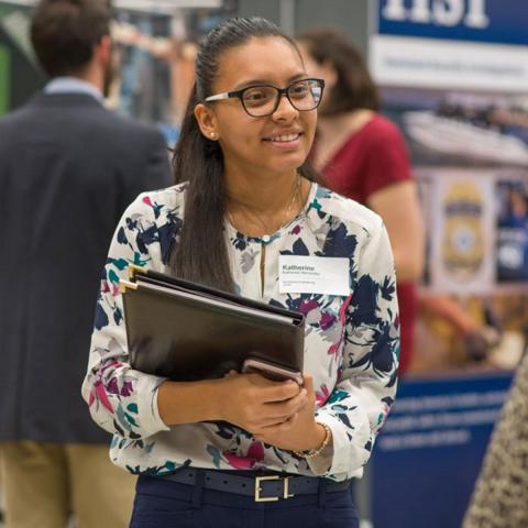 CEPS student smiling and holding binder at Career Services fair