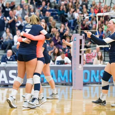 UNH volleyball players hugging after scoring a point