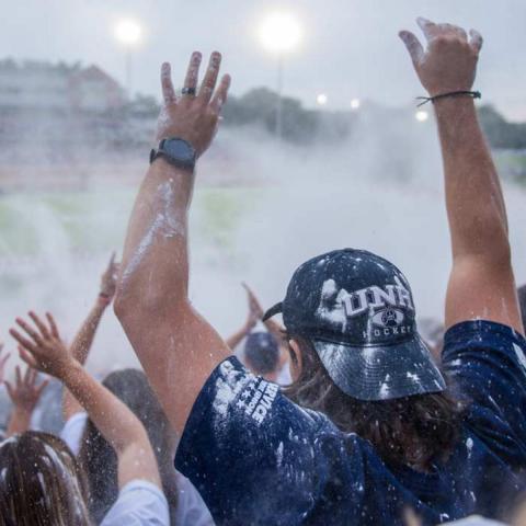 Students covered in white chalk cheering in student section at Wildcat Stadium
