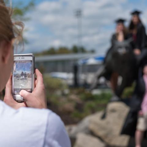 Students taking graduation photos on the wildcat statue